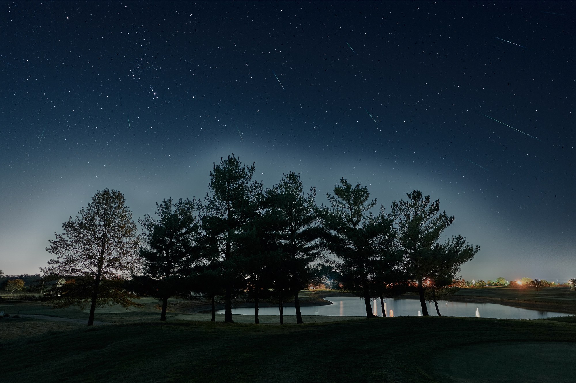 Orionidy nad polem golfowym, zdjęcie złożone z wielu ekspozycji. Smugi meteorów zbiegają się w okolicy gwiazdozbioru Oriona, widocznego w lewej górnej części kadru
