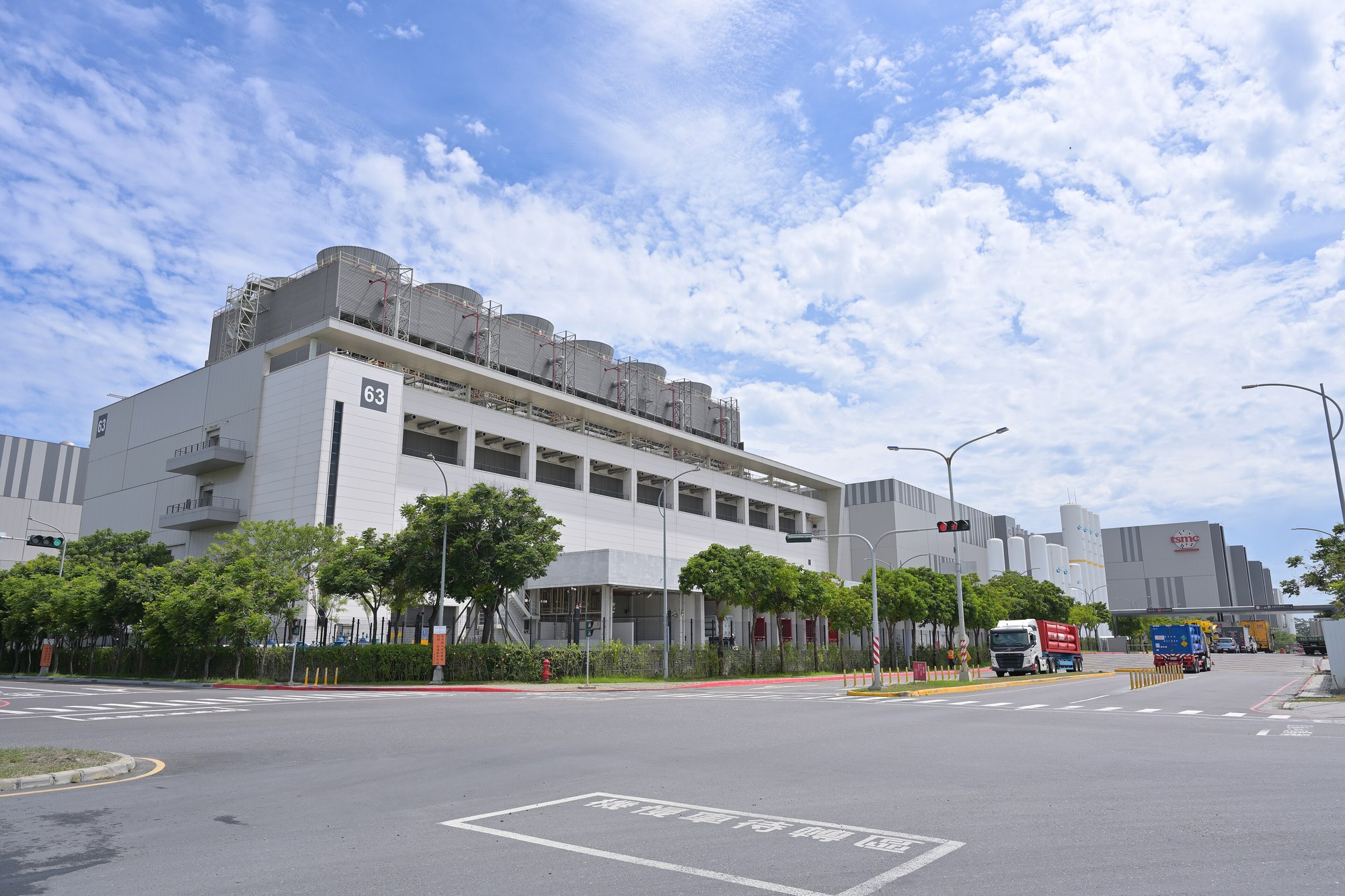 Fab 18 TSMC w Southern Taiwan Science Park, maj 2025: wieże chłodnicze na dachu, rząd białych zbiorników i ciężarówki przy bramie. Kasa całego wyścigu stoi właśnie tutaj